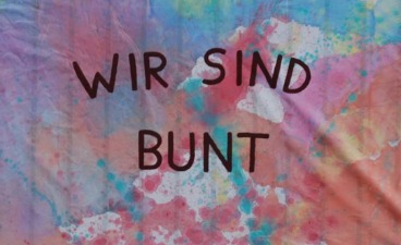 Foto eines bunt bemalten Tuchs mit der Aufschrift "Wir sind bunt": Sommerfest im BTZ Braunschweig-Wolfsburg